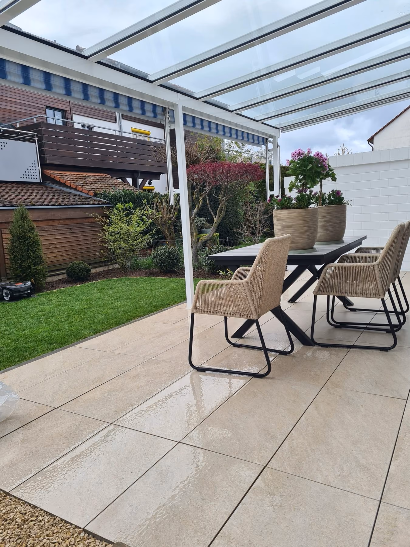 Überdachte Terrasse mit Glasdach, Essplatz und angrenzender Rasenfläche