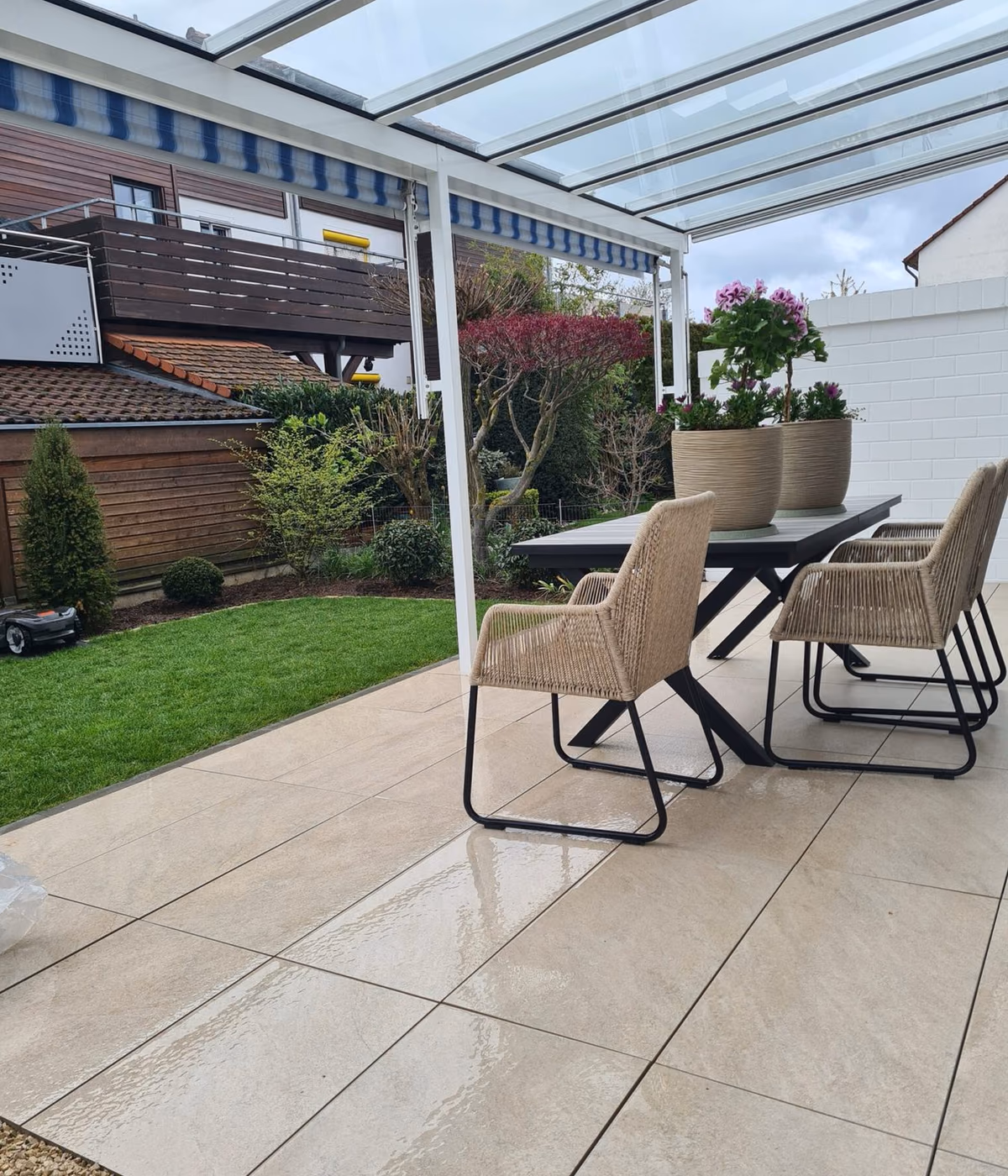 Überdachte Terrasse mit Glasdach, Essplatz und angrenzender Rasenfläche