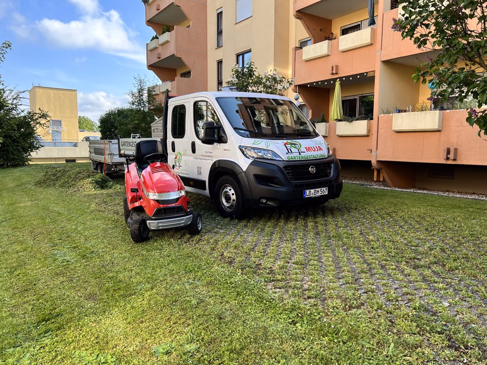 Firmenfahrzeug mit Aufsitzmäher im Innenhof einer Wohnanlage