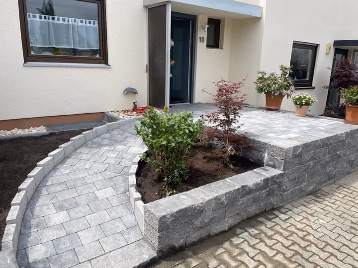 Halbrundes Hochbeet aus Granit-Kleinpflaster im Eingangsbereich eines Wohnhauses