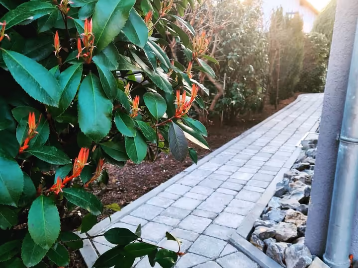 Gartenweg aus hellem Kleinpflaster mit Granit-Randstein und angrenzendem Kiesstreifen