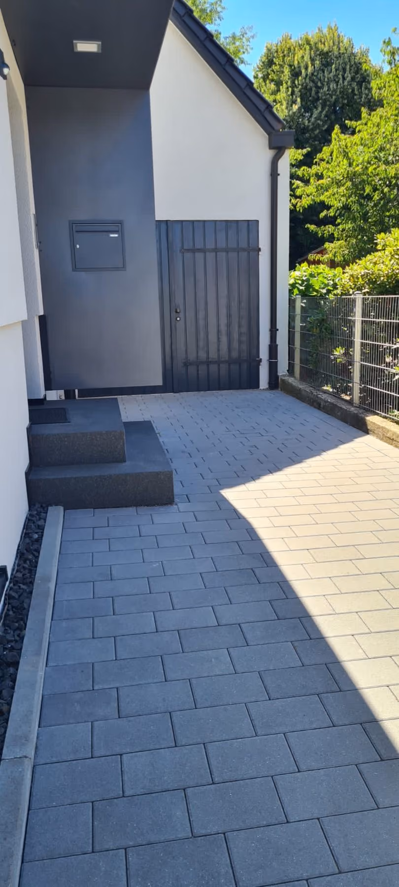 Zugang mit dunklen Blockstufen und zweifarbigem Pflasterbelag zur Haustür