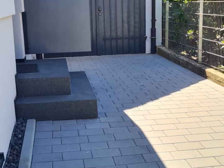 Zugang mit dunklen Blockstufen und zweifarbigem Pflasterbelag zur Haustür