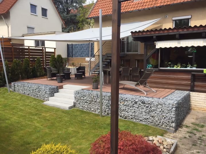 Terrassenstufen mit Gabionen als seitliche Stützelemente, davor eine Rasenfläche