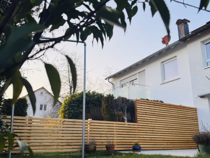 Niedriger Holzlattenzaun als Terrassenabgrenzung mit Rasen im Vordergrund