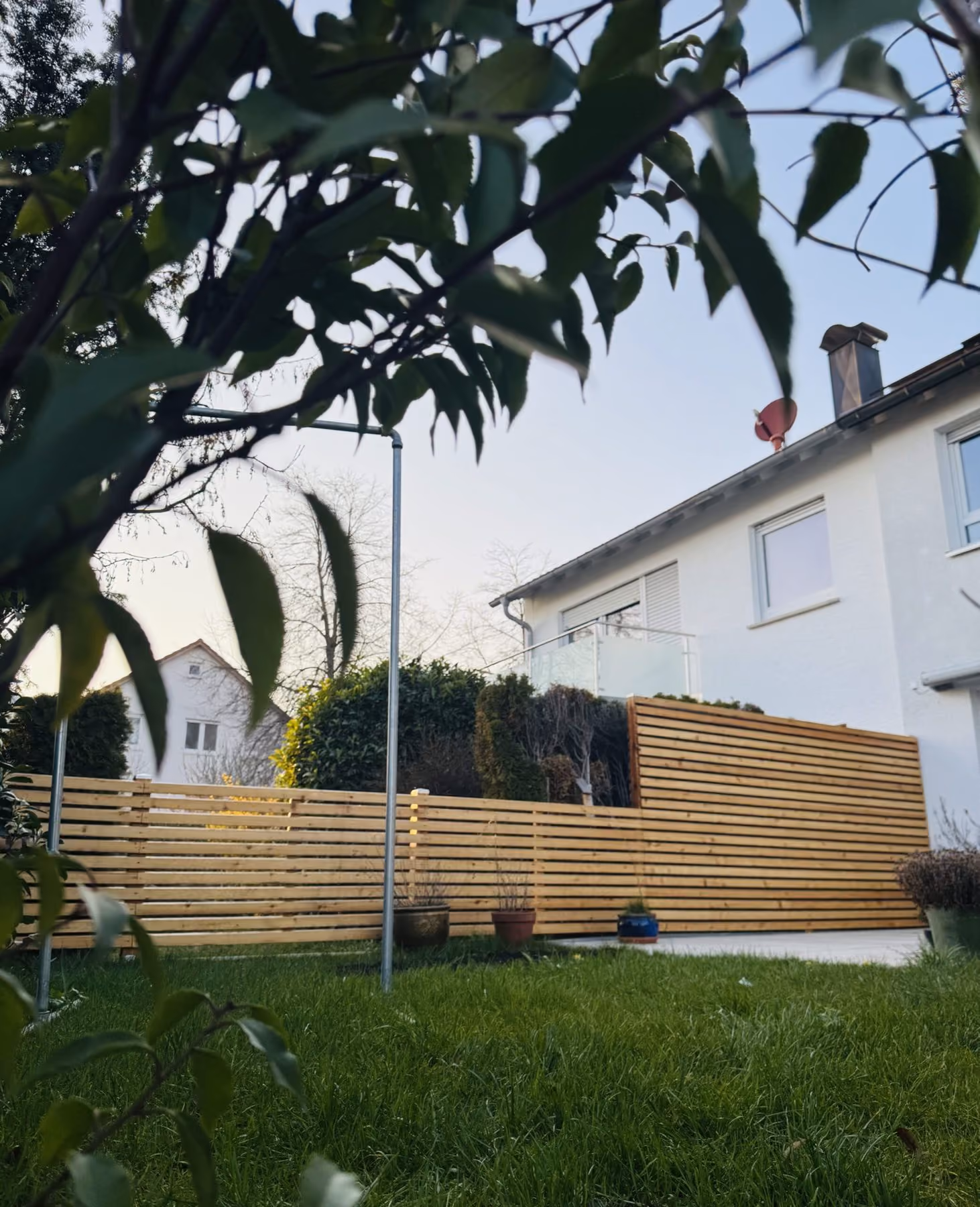 Niedriger Holzlattenzaun als Terrassenabgrenzung mit Rasen im Vordergrund